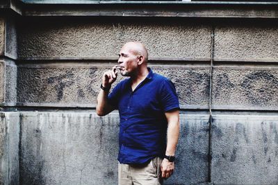 Man smoking while standing against wall