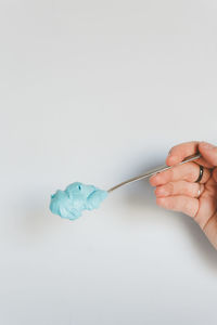 Close-up of hand holding a spoon full of blue cream 