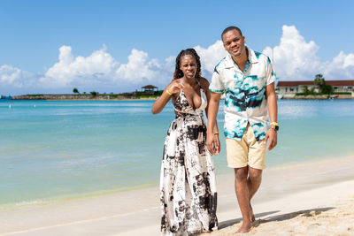 Portrait of smiling friends standing at beach