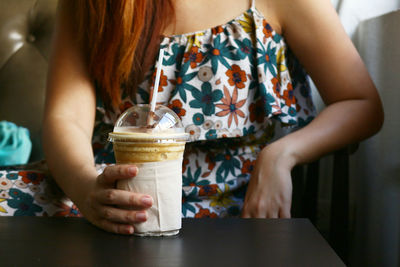 Midsection of woman drinking glass on table