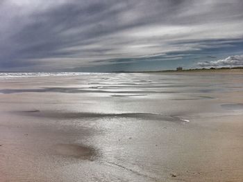 Scenic view of beach against cloudy sky