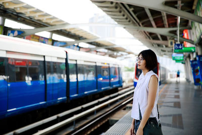 Rear view of woman standing at railroad station