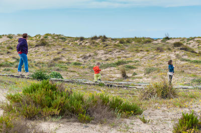 Full length of woman with kids on land against sky