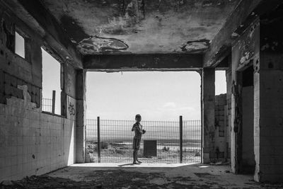 Full length of boy standing at abandoned building