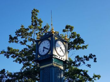 Low angle view of clock tower against clear blue sky