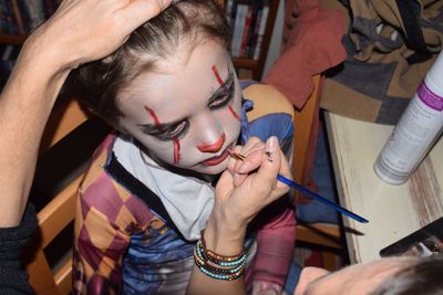 Cropped hand doing halloween make-up for boy