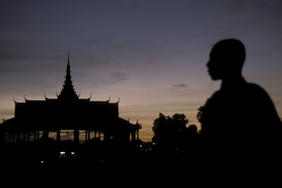 Silhouette people outside building against sky during sunset