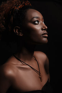 Portrait of young woman looking away over black background