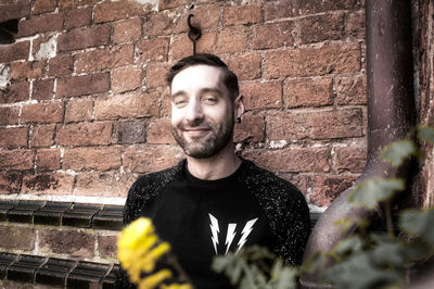 Portrait of man standing against brick wall