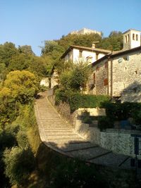 Footpath amidst trees and buildings against sky