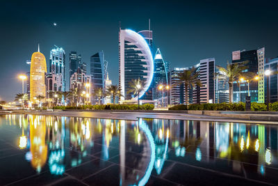 Illuminated modern buildings against sky at night