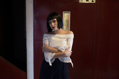 Young woman standing against door