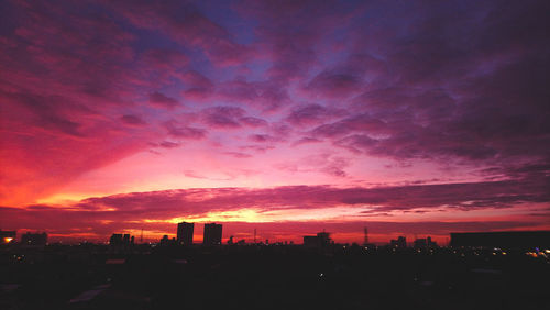 Scenic view of dramatic sky over city during sunset