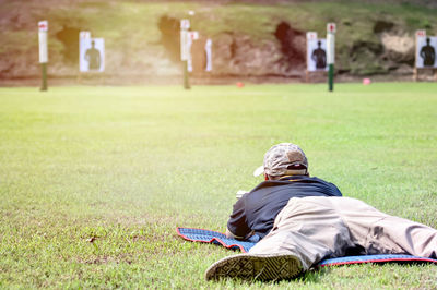 Rear view of man relaxing on field