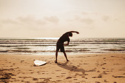 Rear view of man exercising at beach