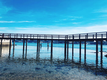 Pier over sea against blue sky