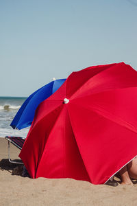 Rear view of woman with umbrella on beach against clear sky