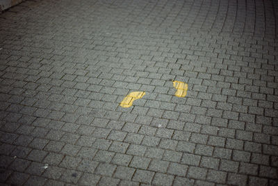 High angle view of yellow arrow symbol on footpath