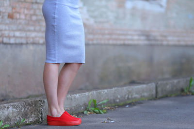 Low section of woman standing against wall