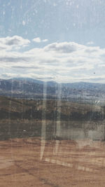 Scenic view of landscape against sky seen through glass window