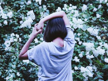 Rear view of teenage girl standing against white flowers