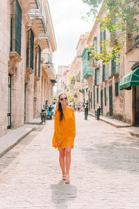 Full length portrait of woman walking on street amidst buildings