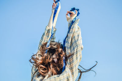 Low angle view of woman against clear blue sky