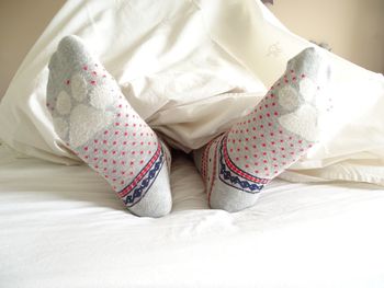 Low section of woman wearing socks relaxing on bed at home