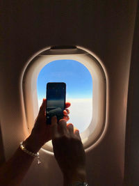 Close-up of person using mobile phone in airplane