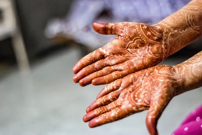 Cropped image of woman showing henna tattoo on hands