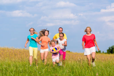 Family running by plants against sky