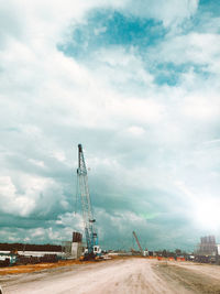 Electricity pylon by road against sky in city