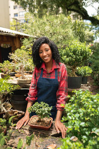 Portrait of young woman standing by plants