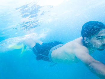 Shirtless man swimming in sea