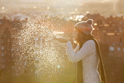 Side view of young woman blowing snow