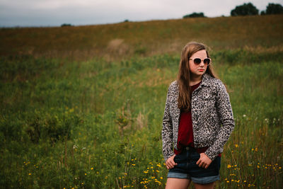 Young woman wearing sunglasses standing in field