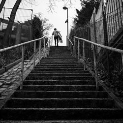 Low angle view of man carrying bicycle while climbing on stairs