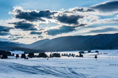 Scenic view of mountains against cloudy sky on sunny day