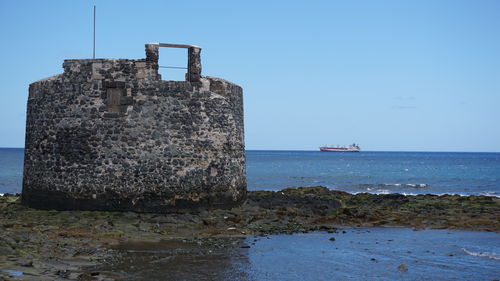 Built structure on beach against clear sky