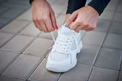 Low section of woman tying shoelace on footpath