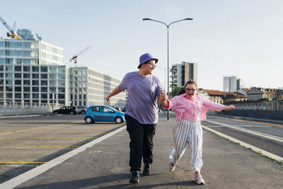 Happy brother and sister with down syndrome holding hands running on street