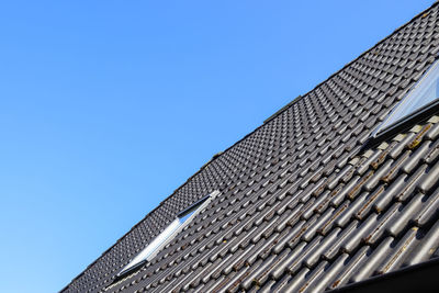 Low angle view of roof of building against clear blue sky