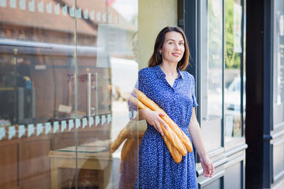 Young woman buying a french baguette