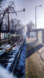 Railroad track by bare trees during winter