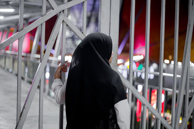 Rear view of woman in hijab standing by gate