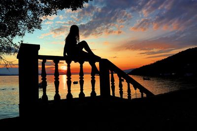 Silhouette woman by sea against sky during sunset