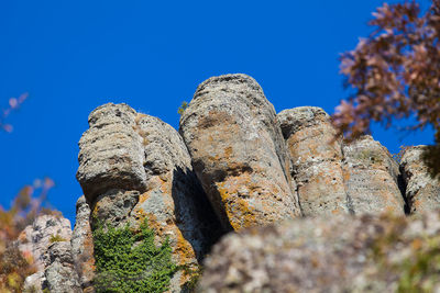 Low angle view of rock formation against clear blue sky