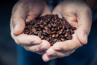 Cropped image of hand holding roasted coffee beans