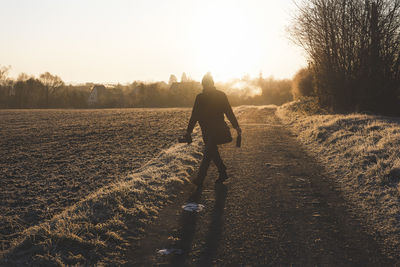 Rear view of man walking on field during winter