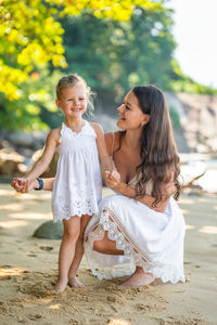 Side view of smiling young woman sitting on beach